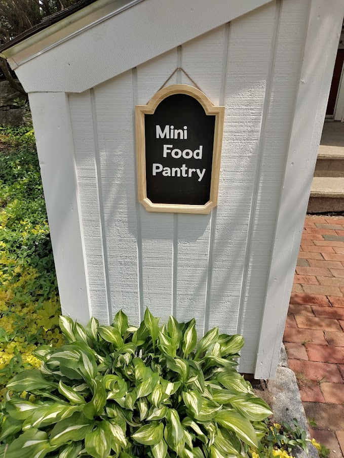 picture of mini food pantry sign on the side of the white structure